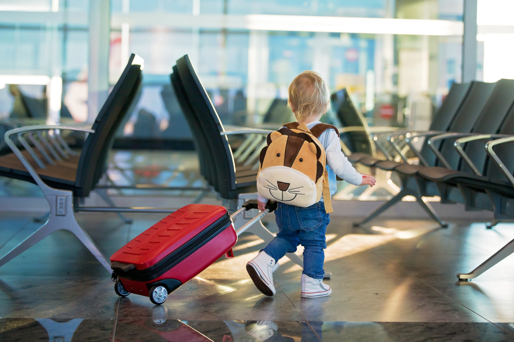 Bambino in aeroporto con il suo trolley