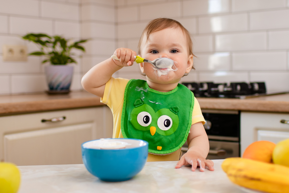 Bambina che mangia da una tazza in cucina