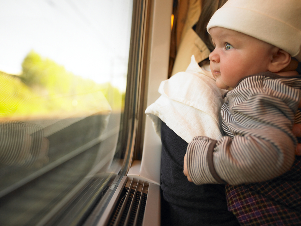 Neonato guarda dal finestrino di un treno in corsa