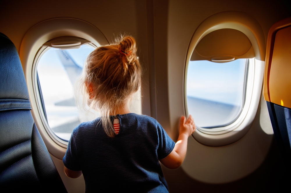 Bambina che guarda fuori dai finestrini dell'aereo