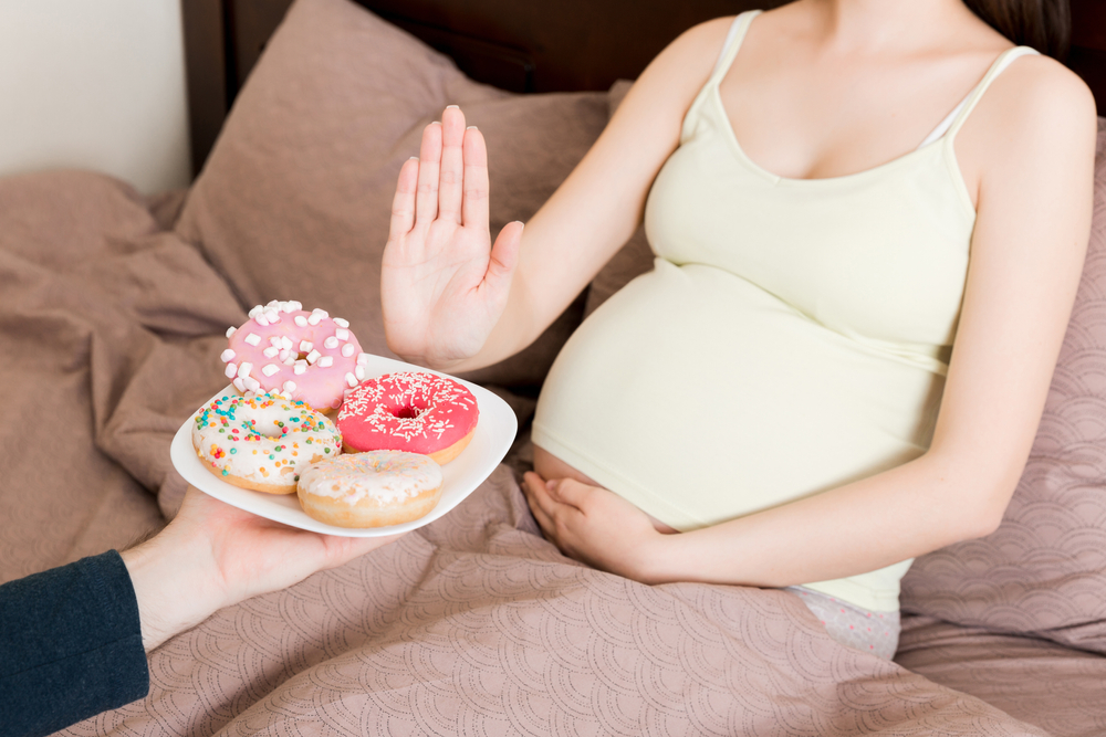 Donna incinta che rifiuta un piatto di dolciumi