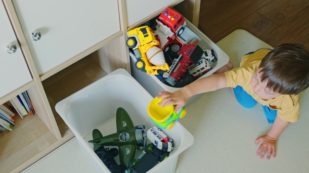 Bambino che rimette a posto i suoi giocattoli nella cameretta