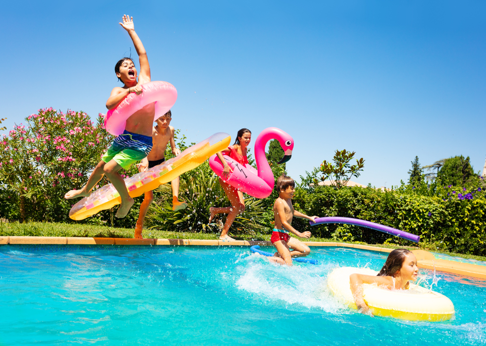 Bambini che saltano con dei gonfiabili in acqua in una piscina e si divertono