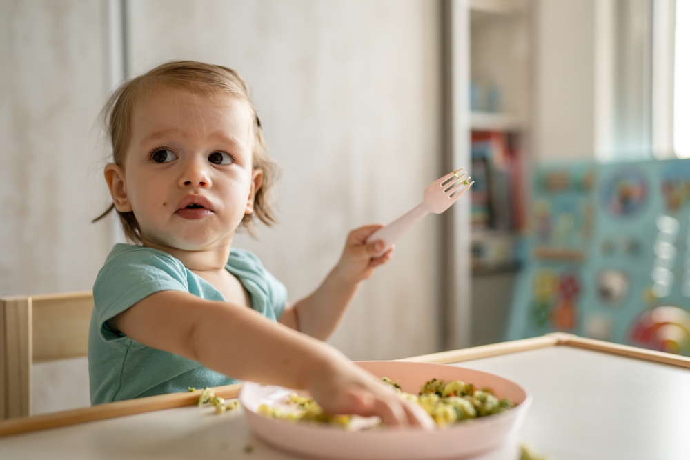 Bambina con la bocca sporca che mangia con le mani nel piatto