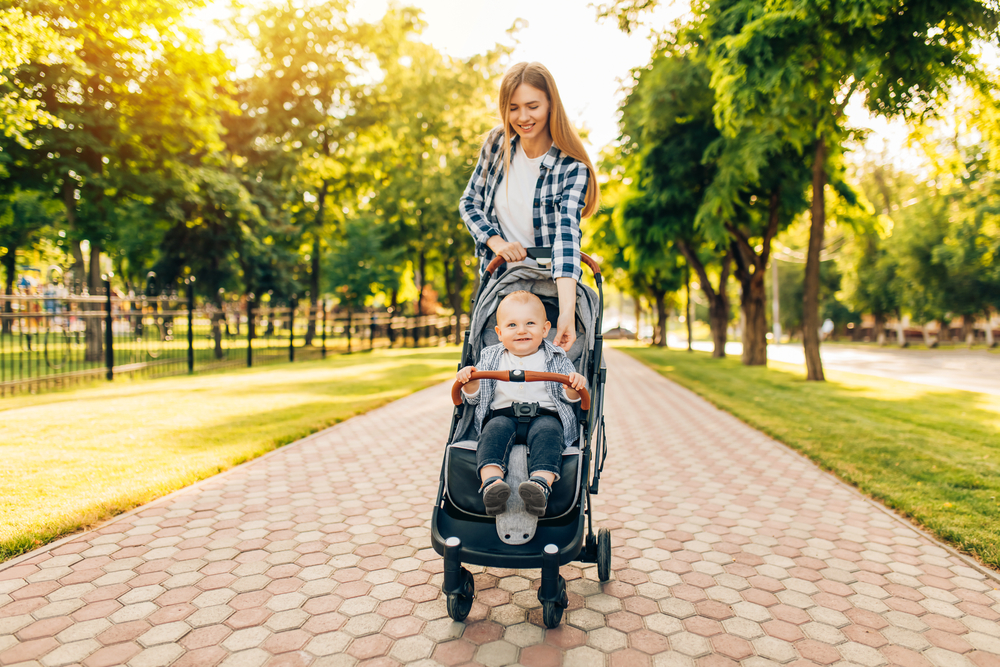 Mamma che porta a spasso il bambino per il parco con il passeggino