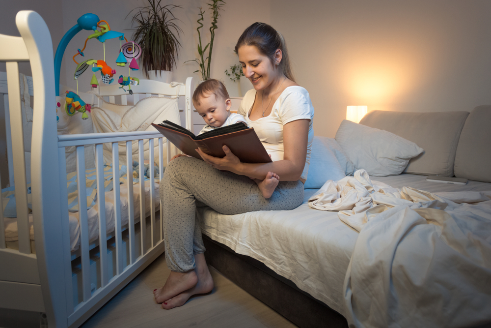 Madre seduta sul letto che legge una storia al suo bambino prima di andare a dormire