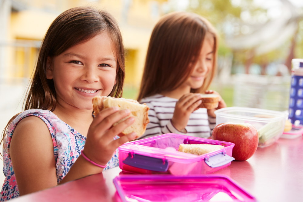 Bambine sorridenti che mangiano un panino al sacco