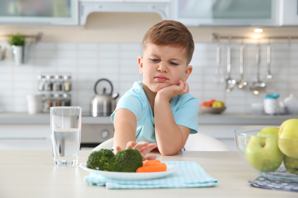 Bambino che rifiuta di mangiare verdure a tavola in cucina