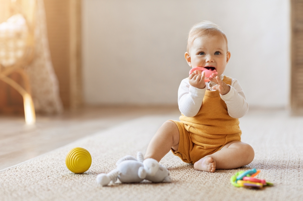 Bambino felice che gioca con i giocattoli mentre è seduto sul pavimento