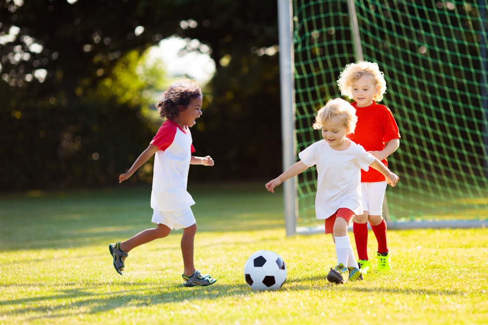 Tre bambini che giocano a calcio in un campo all'aperto