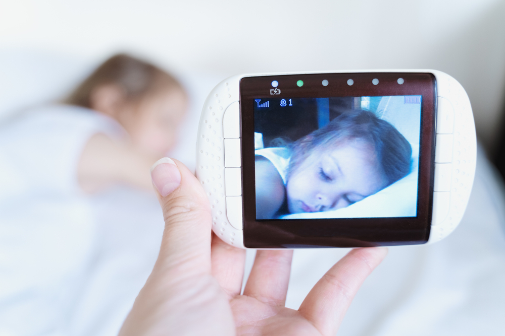 Madre che osserva la bambina dormire tramite il video del baby monitor