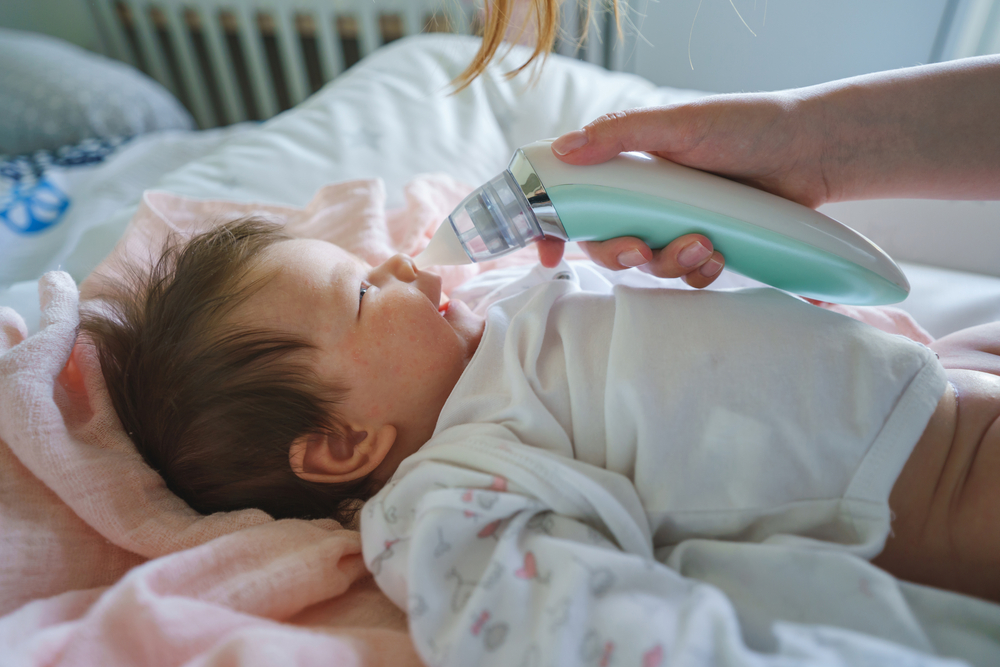 Madre che aspira il muco al neonato con un aspiratore nasale elettrico