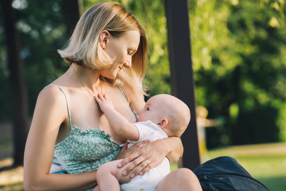 Mamma che allatta al seno il suo bambino nella natura