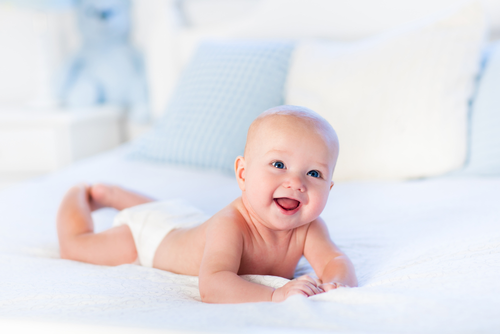 Neonato durante il tummy time sdraiato a pancia in giù sul letto