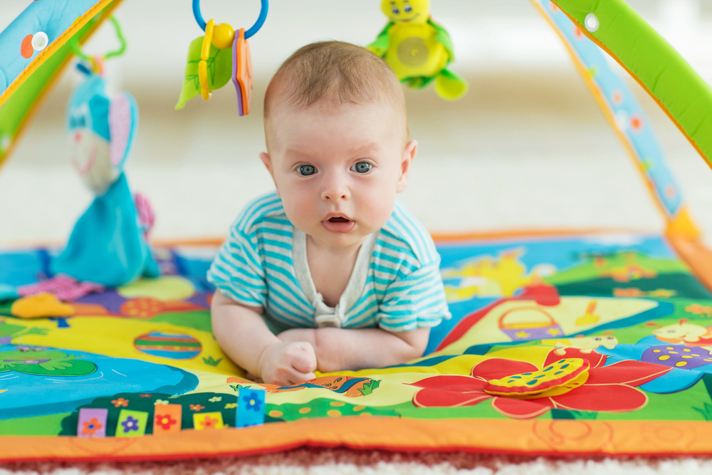 Neonato sdraiato su un tappetino multisensoriale durante il tummy time