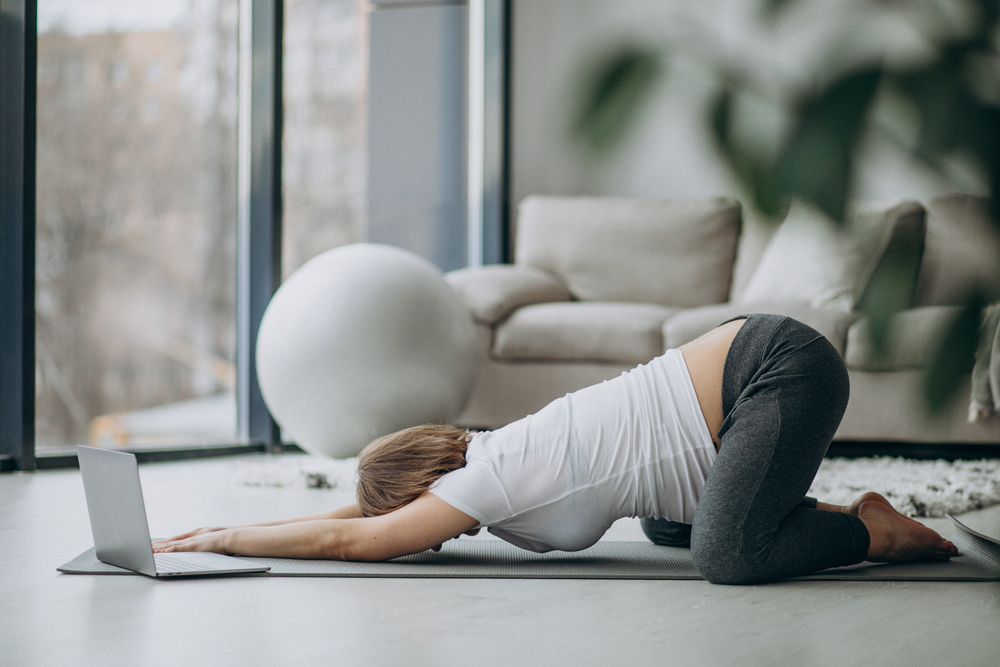 Donna incinta che pratica yoga sdraiata su un materassino sul pavimento