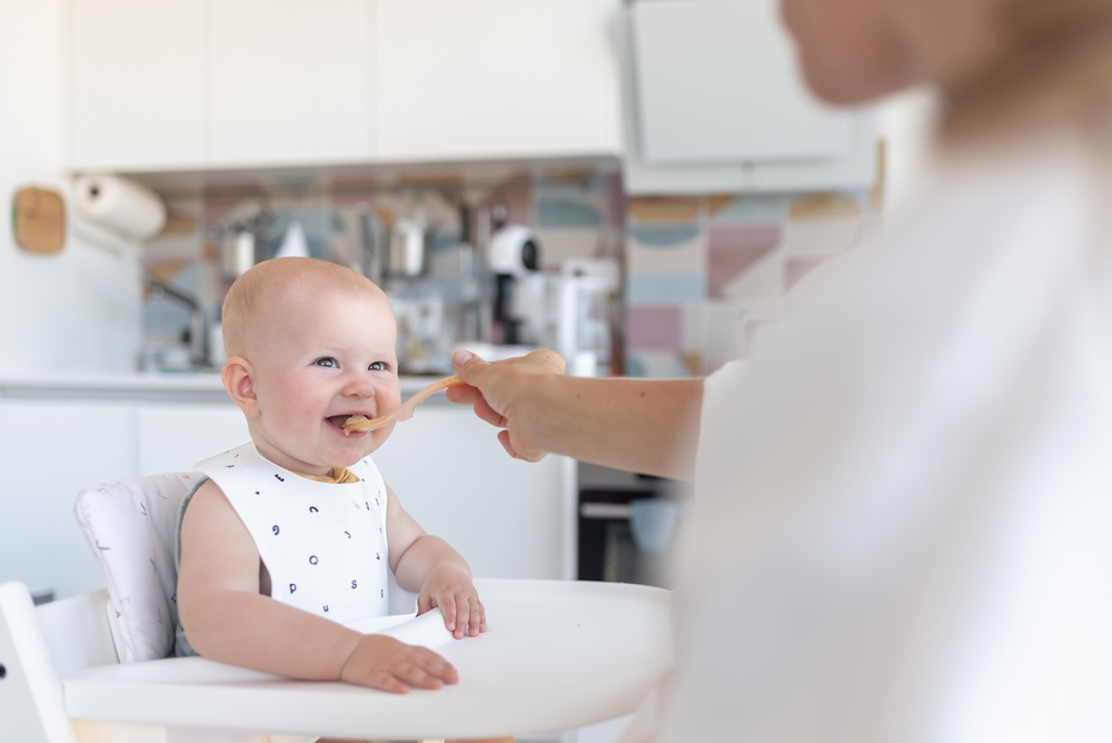 Madre che imbocca il suo bambino con un cucchiaio durante l’alimentazione complementare