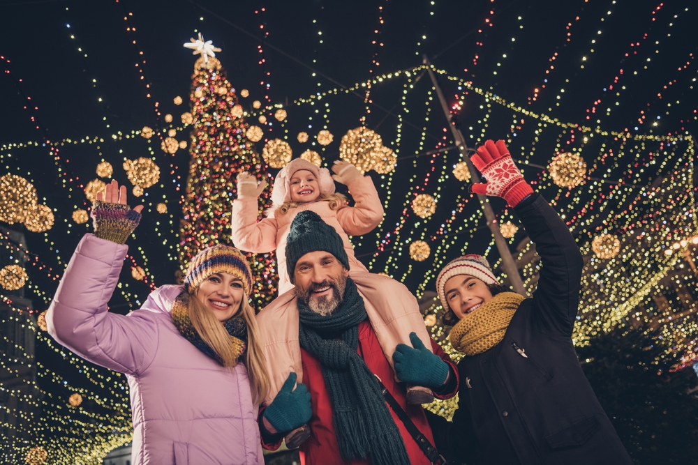 Famiglia felice in una città natalizia, con albero di Natale e luci sullo sfondo