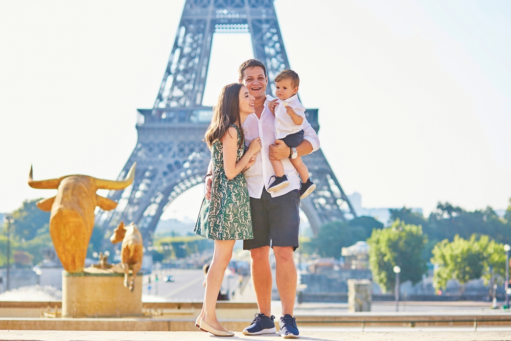 Famiglia con madre, padre e bambino in piedi davanti alla Torre Eiffel