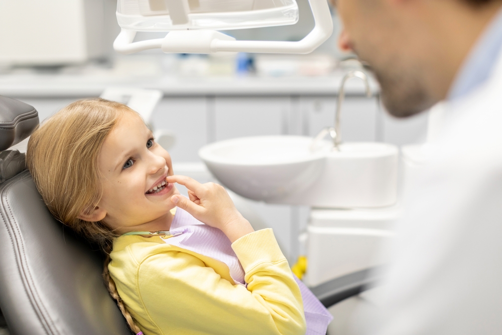 Bambina mostra i denti al dentista pediatrico