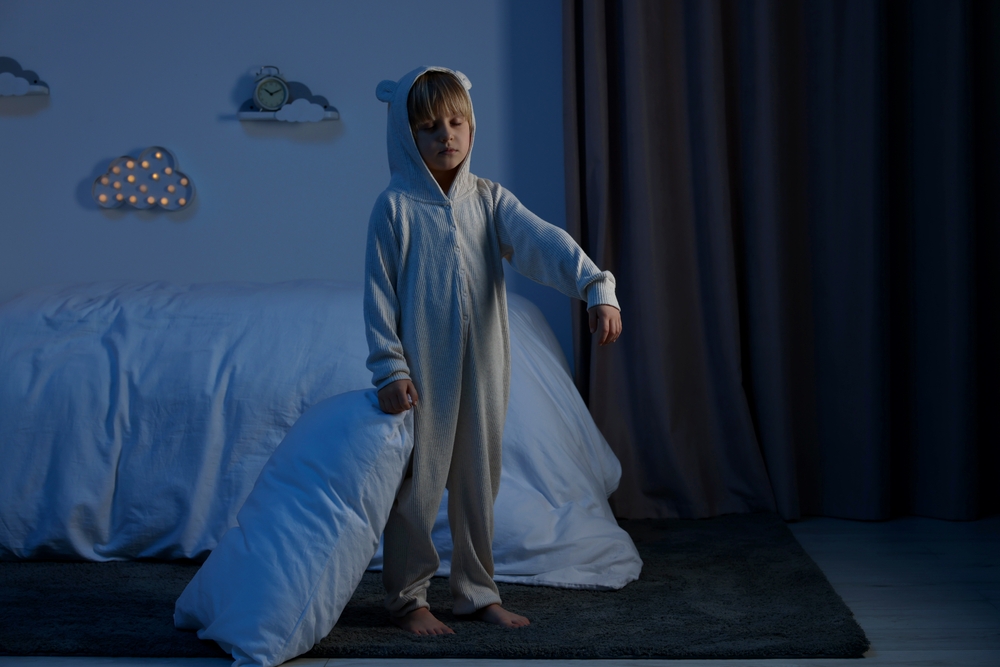 Bambino in pigiama che cammina nel sonno con un cuscino in mano nella sua cameretta