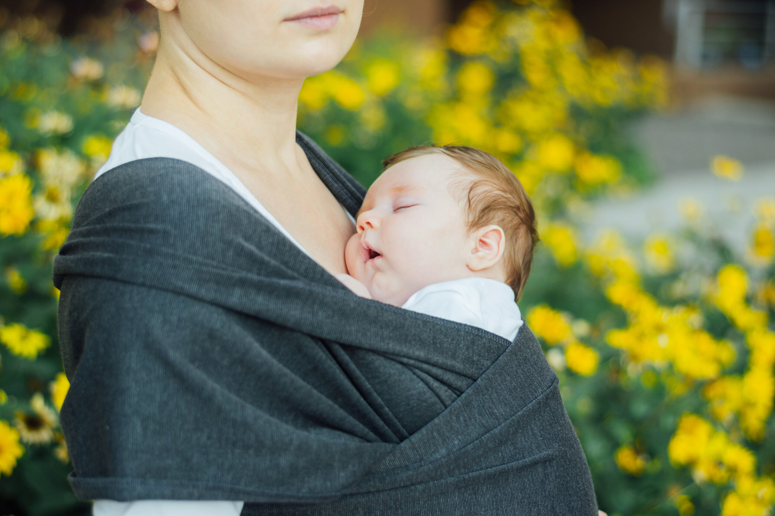 Donna che pratica babywearing con un neonato addormentato in fascia